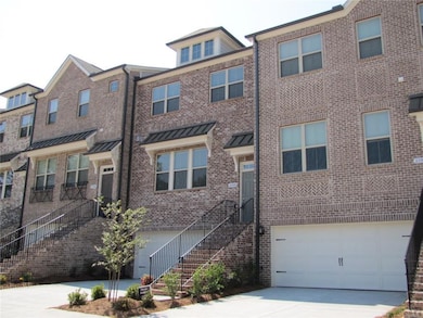 Townhome / multi-family property featuring concrete driveway, a garage, brick siding, and stairs
