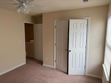 Unfurnished bedroom featuring light colored carpet, a textured ceiling, a closet, and ceiling fan