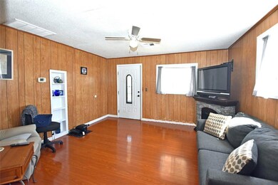 Living room with ceiling fan, wooden walls, hardwo