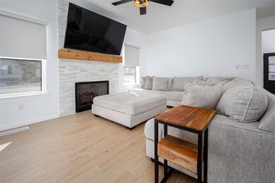 Living area featuring a fireplace, light wood finished floors, visible vents, ceiling fan, and baseboards