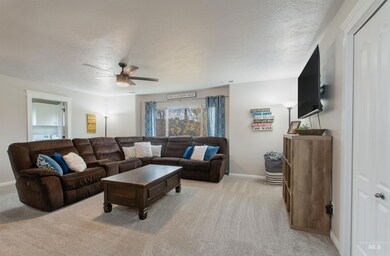 Living room with a textured ceiling, light colored carpet, and ceiling fan