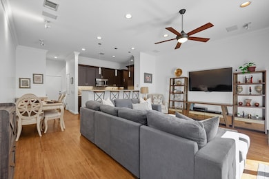 Living room with crown molding, recessed lighting, light wood-style floors, and ceiling fan