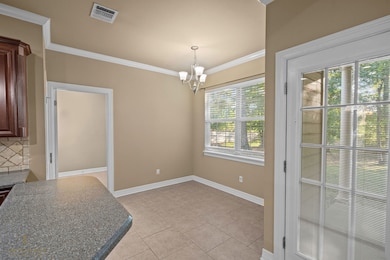 Unfurnished dining area with ornamental molding, a chandelier, and light tile patterned floors