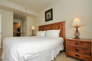 Bedroom with ensuite bathroom, light carpet, and a closet