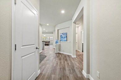Corridor featuring wood finished floors, a textured wall, and recessed lighting