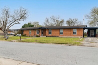 View of front of home featuring driveway, an attached carport, and a front yard