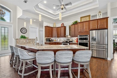 Kitchen with stainless steel appliances, new hanging light fixtures, decorative backsplash, a breakfast bar area, and light stone counters, and new designer stools