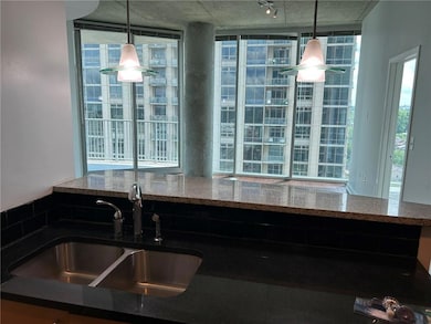 Kitchen featuring a sink, stone counters, and decorative light fixtures
