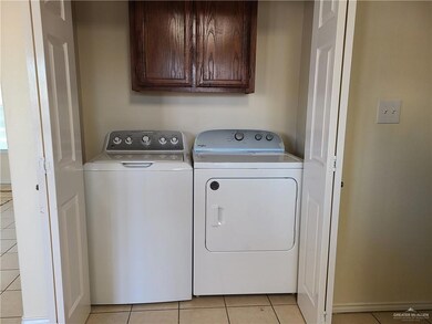 Laundry room featuring washer and dryer, light tile patterned floors, and cabinet space