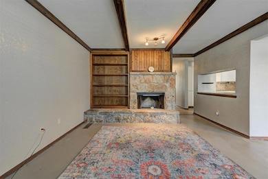 Living room featuring concrete floors, beamed ceiling, baseboards, and a fireplace
