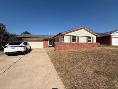 Ranch-style house featuring a garage, concrete driveway, a front lawn, and brick siding
