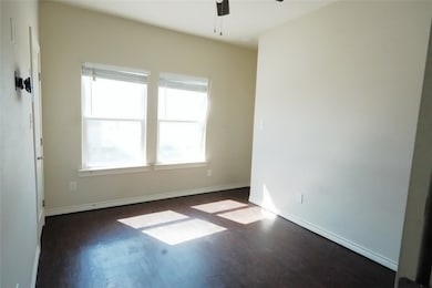 Empty room with ceiling fan, dark wood finished fl