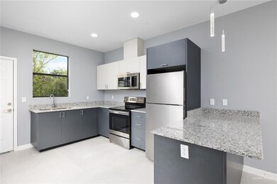 Kitchen with appliances with stainless steel finishes, hanging light fixtures, kitchen peninsula, white cabinets, and sink