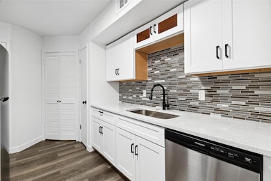 Kitchen with dark wood-type flooring, sink, stainl