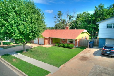 View of front of home featuring driveway, a garage, brick siding, and a chimney