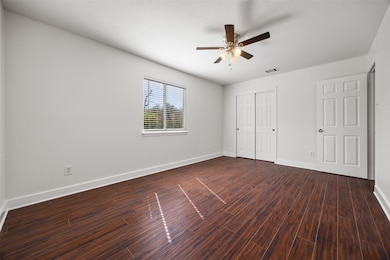 Unfurnished bedroom with a ceiling fan, dark wood-type flooring, and a closet