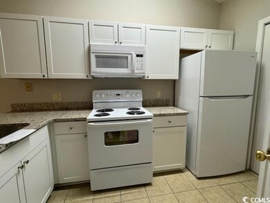 Kitchen featuring white cabinetry, light tile patt