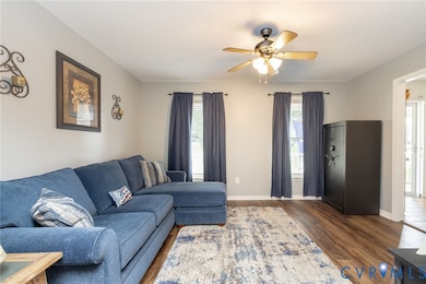 Living room featuring dark wood-type flooring and ceiling fan