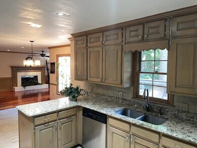 Kitchen with dishwasher, a sink, a peninsula, light stone counters, and ornamental molding