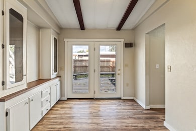 Doorway featuring beamed ceiling and wood finished floors