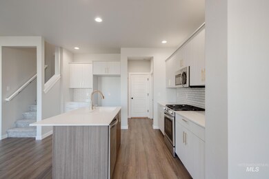 Kitchen with stainless steel appliances, white cabinets, a center island with sink, decorative backsplash, and recessed lighting