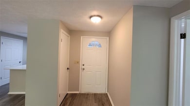 Doorway to outside featuring a textured ceiling and wood finished floors