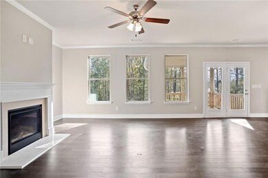 Unfurnished living room featuring crown molding, dark wood-type flooring, a glass covered fireplace, and a ceiling fan