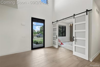 Entrance foyer featuring light wood-style flooring, a barn door, and a towering ceiling
