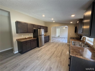 Kitchen featuring dark countertops, light wood-style flooring, a textured ceiling, appliances with stainless steel finishes, and ceiling fan