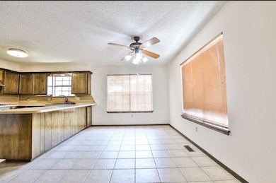 Kitchen with a sink, light countertops, a textured ceiling, a ceiling fan, and a peninsula