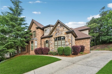 View of front of house with stone siding, a front yard, a shingled roof, and driveway
