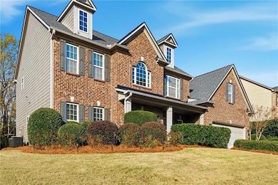 View of front of property with brick siding, a front lawn, and roof with shingles