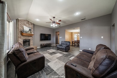 Living room with a ceiling fan, lofted ceiling, wood finished floors, a fireplace, and a chandelier