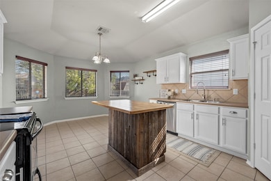 Kitchen with white cabinetry, wooden counters, a kitchen island, and light tile patterned flooring