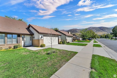 View of green lawn featuring driveway, a garage, and a mountain view