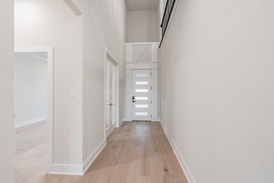 Corridor with a high ceiling and light wood-style flooring