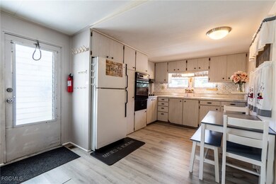 Kitchen with light wood-style vinyl floors, freestanding refrigerator, decorative backsplash, and light countertops