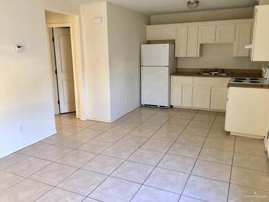 Kitchen with white appliances, light tile patterned floors, dark countertops, and white cabinetry