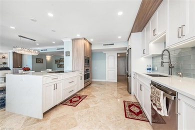 Kitchen with a sink, white cabinets, stainless steel appliances, light countertops, and backsplash