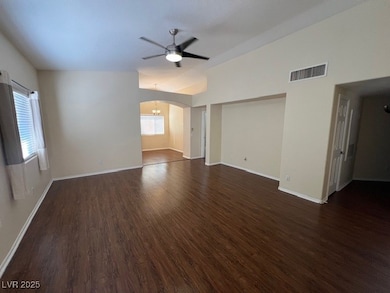Unfurnished living room with dark wood-style flooring, ceiling fan, arched walkways, and vaulted ceiling