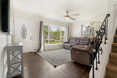 Living room with ceiling fan and dark wood-type flooring