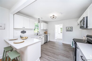 Kitchen with white cabinets, light countertops, a kitchen island, light hardwood floors, and stainless steel appliances