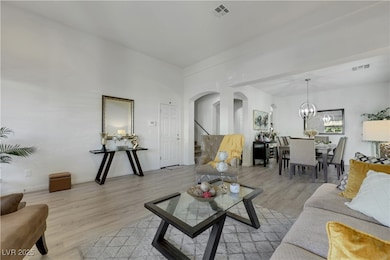 Living room with arched walkways, light wood-style