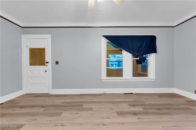 Empty room featuring ceiling fan, light hardwood / wood-style floors, and ornamental molding