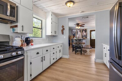 Kitchen featuring appliances with stainless steel finishes, white cabinetry, light countertops, decorative backsplash, and light wood-style floors