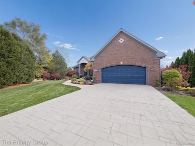 View of front of house featuring decorative driveway, a front lawn, brick siding, and a garage