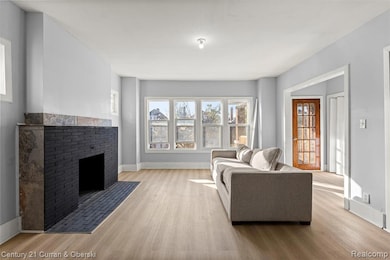 Living area featuring plenty of natural light, wood finished floors, and a brick fireplace