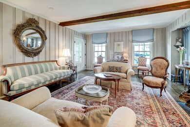 Wood paneling and wide-plank wood flooring continue on into living room. Wood ceiling beams.