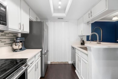 Kitchen featuring white cabinets, light countertops, dark wood-style flooring, stainless steel appliances, and a textured ceiling