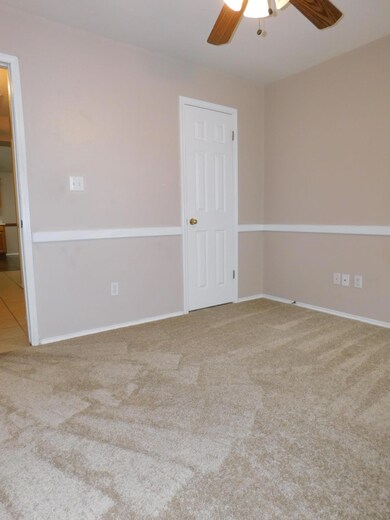 Carpeted empty room with a ceiling fan and basebo
